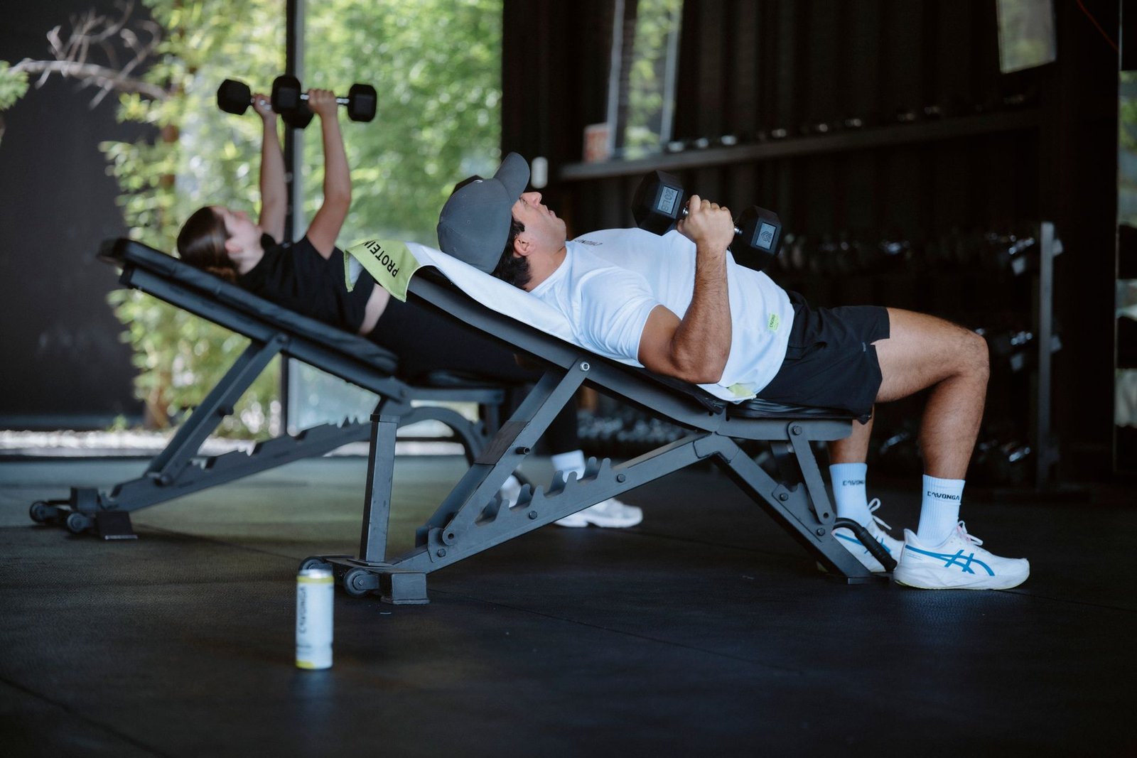 Two people doing dumbbell presses on adjustable benches